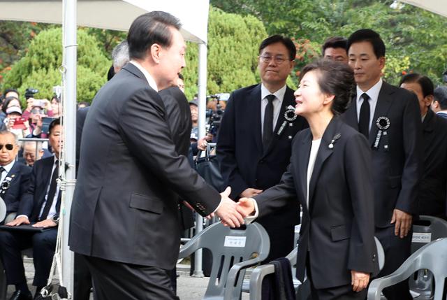 윤석열 대통령이 26일 국립서울현충원에서 열린 박정희 전 대통령 44주기 추도식에서 박근혜 전 대통령과 악수하고 있다.